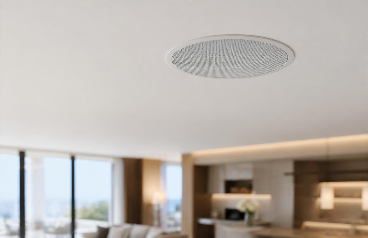 Close-up of a flush-mount in-ceiling speaker integrated into a matte white stretch ceiling with linear cove lighting